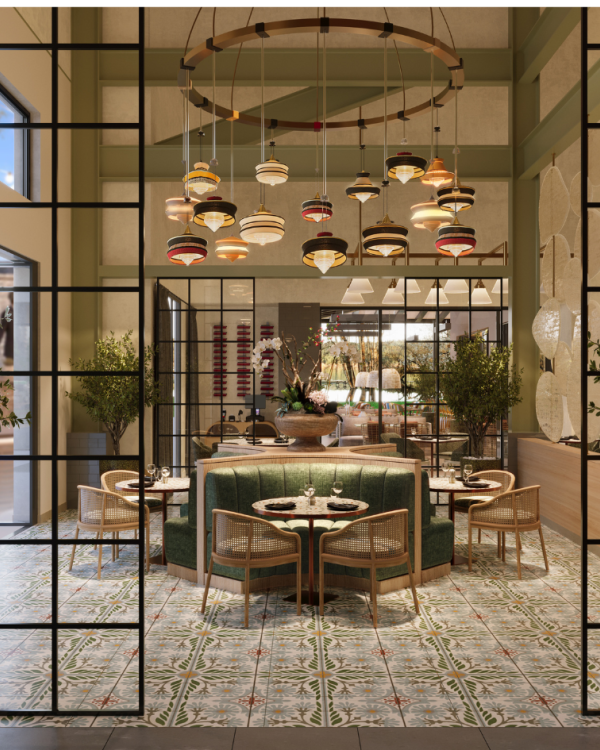 A stylish restaurant interior with a central green booth, round tables, warm lighting, hanging lamps, and glass-paneled entry flanked by potted trees.