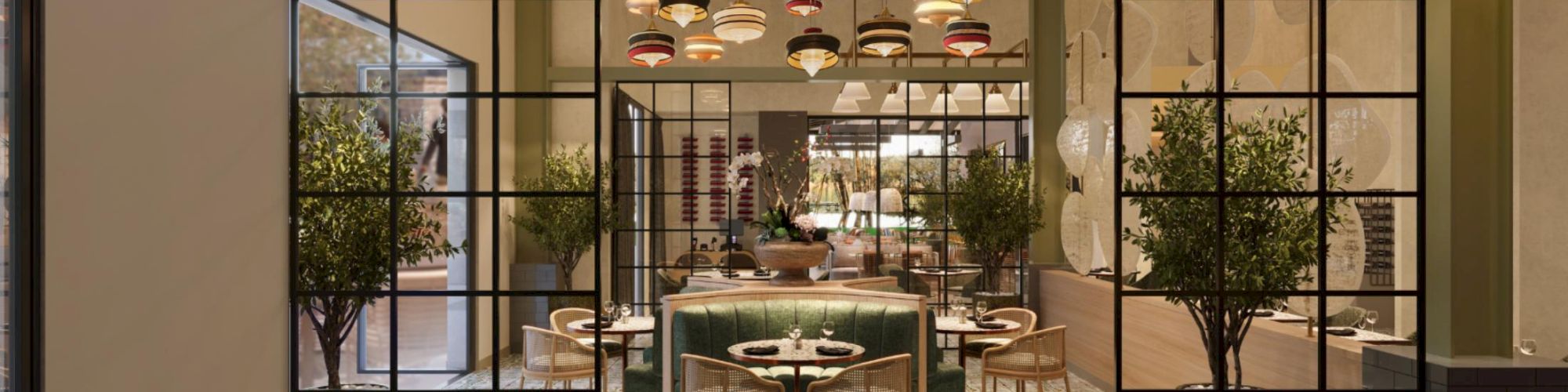 A stylish restaurant interior with a central green sofa, round tables, warm lighting, potted trees, and a grid-framed entryway, inviting and cozy.