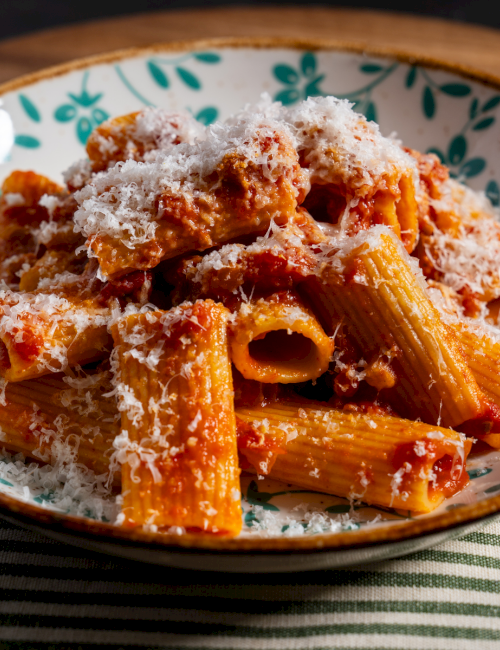 Pasta with tomato sauce and grated cheese served in a decorative bowl, looks hearty and ready to eat, delicious and comforting.
